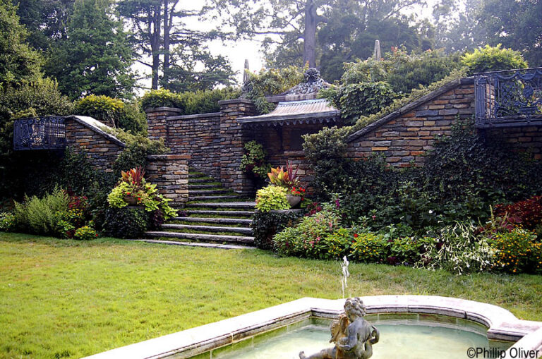 One of the best places to visit in Washington DC this is an image from the Dumbarton Oaks gardens, complete with brick detailings, a short stone staircase, a fountain, and green grass.