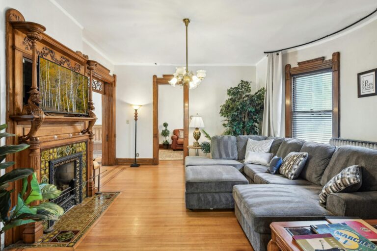 Inviting living room of the Harry F. Legg House, showcasing a beautiful original fireplace, ornate woodwork, and comfortable seating that highlights the home's character.