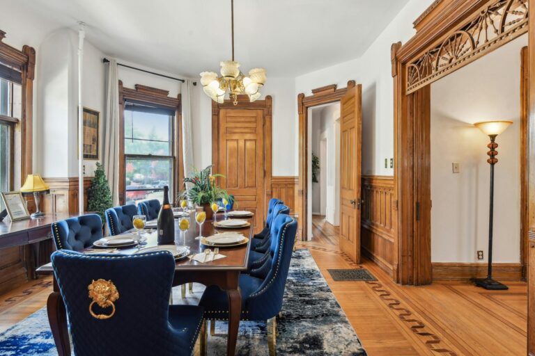 Formal dining room of the Harry F. Legg House, adorned with vintage decor, large windows, and a stunning chandelier, perfect for gathering and entertaining.