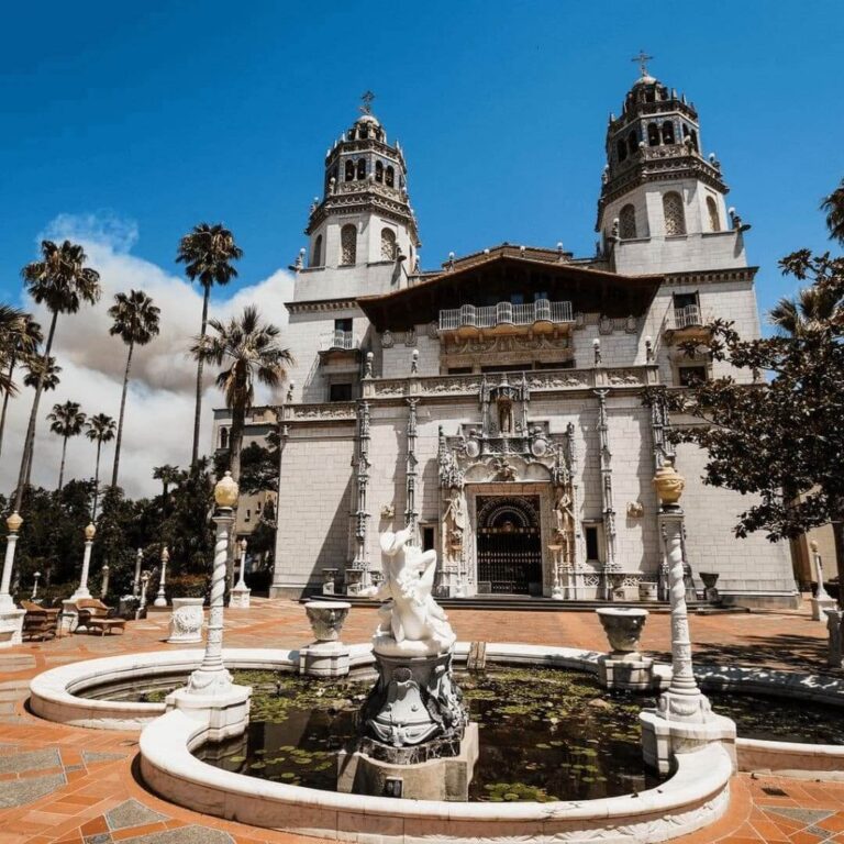 Wide-angle shot of Hearst Castle’s grand entrance with stone steps, palm trees, and classic California sunlight