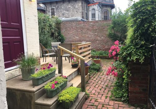 A fabulous home to stay in in Philadelphia for visitors who want to explore downtown Philly, this adorable rental apartment has a back patio and private entrace, pictured here with classic red brick and beautiful folliage.
